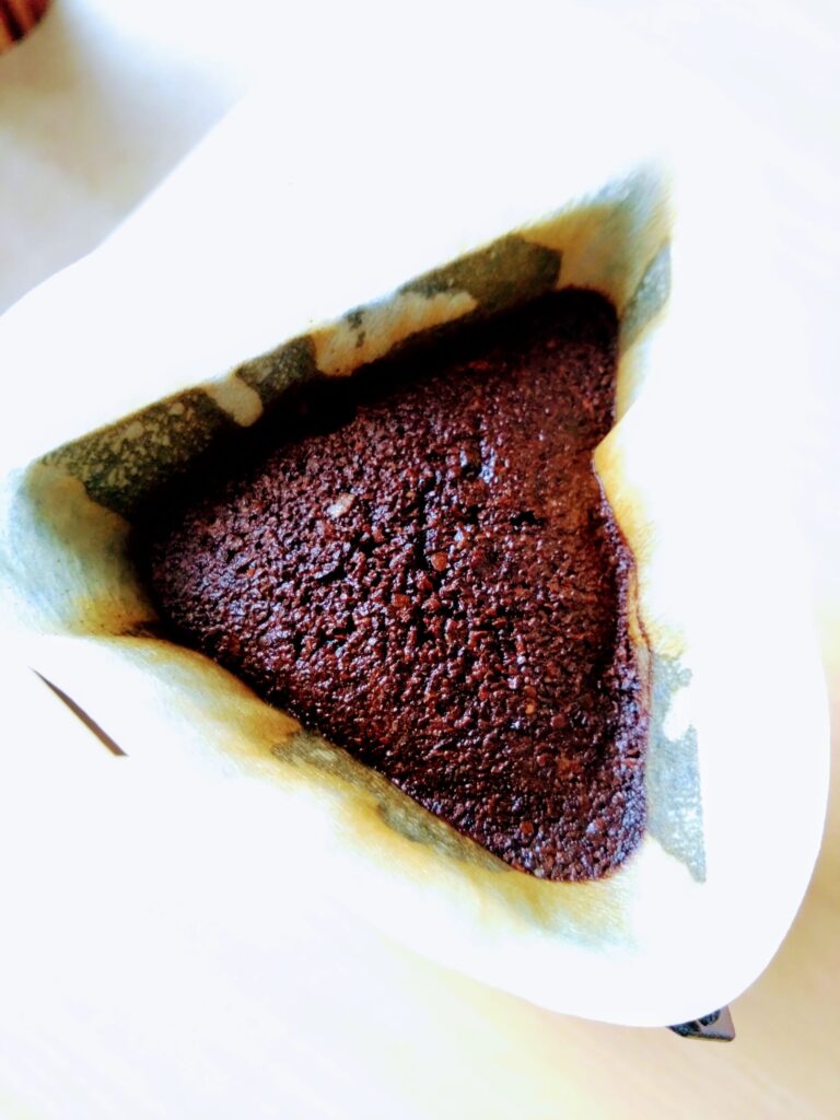 ドリッパー内でドリップ抽出中のコーヒー粉。お湯を含んでふっくらと膨らみ、新鮮なコーヒーの香りが漂ってくる様子。